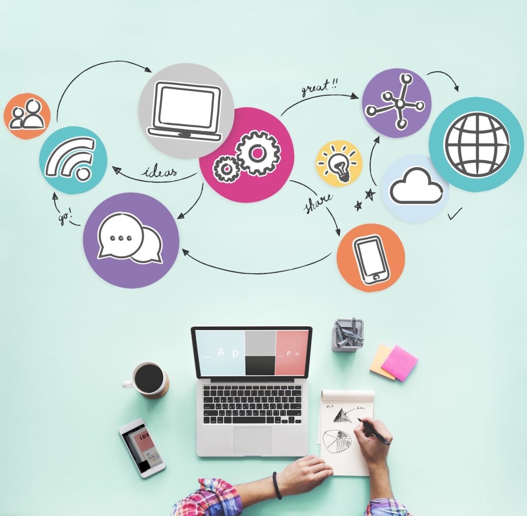 Person arbeitet an Laptop und Smartphone mit Social-Media-Icons, Symbol für vernetztes Marketing und Kampagnenplanung bei QMAX Impact.