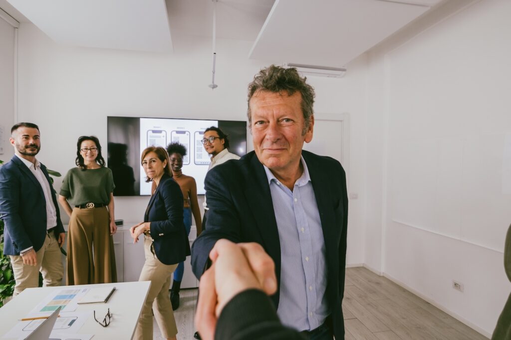 Handschlag zwischen Führungspersonen in einem Meeting – QMAX Public Line unterstützt Städte, Gemeinden und Behörden mit professioneller Öffentlichkeitsarbeit.